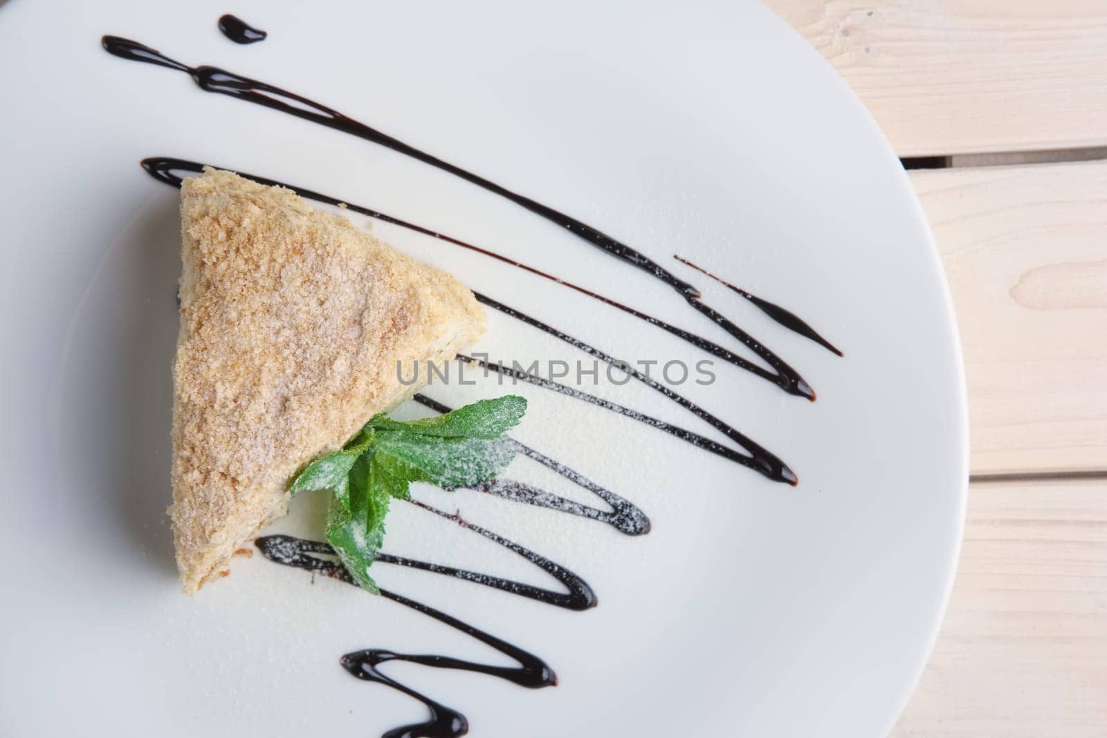 Top view of napoleon cake on plate with chocolate sauce. Puff pastry cake with custard