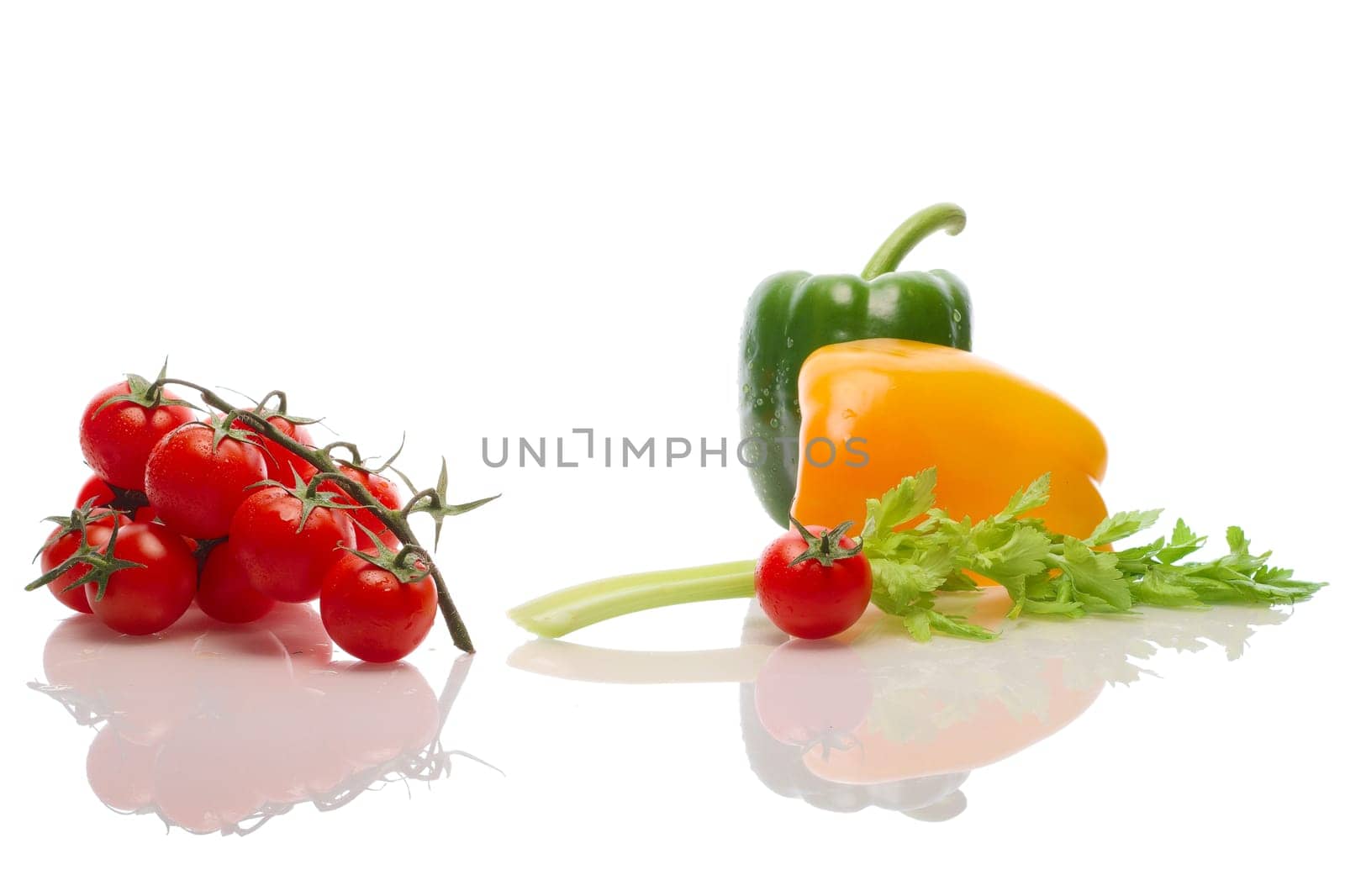 A branch of a tomato, celery and bell pepper with water drops and reflection on white background