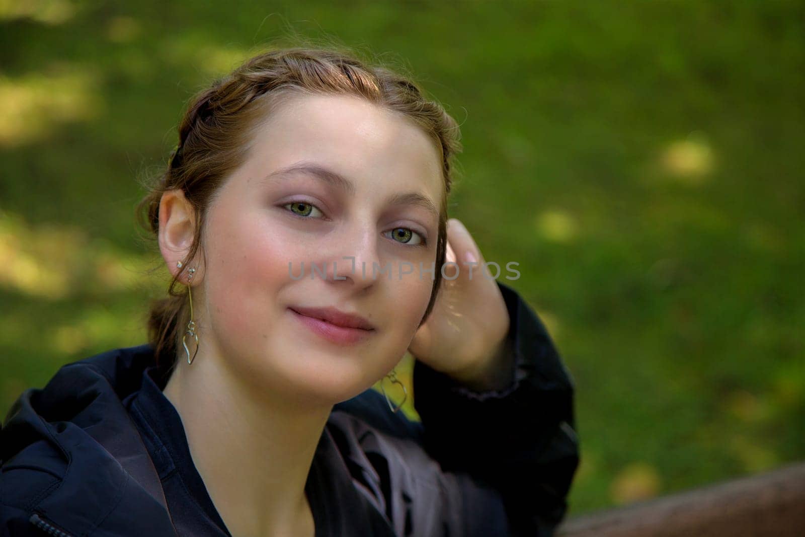 young woman student in a park green grass blonde nice looking girl sitting on bench