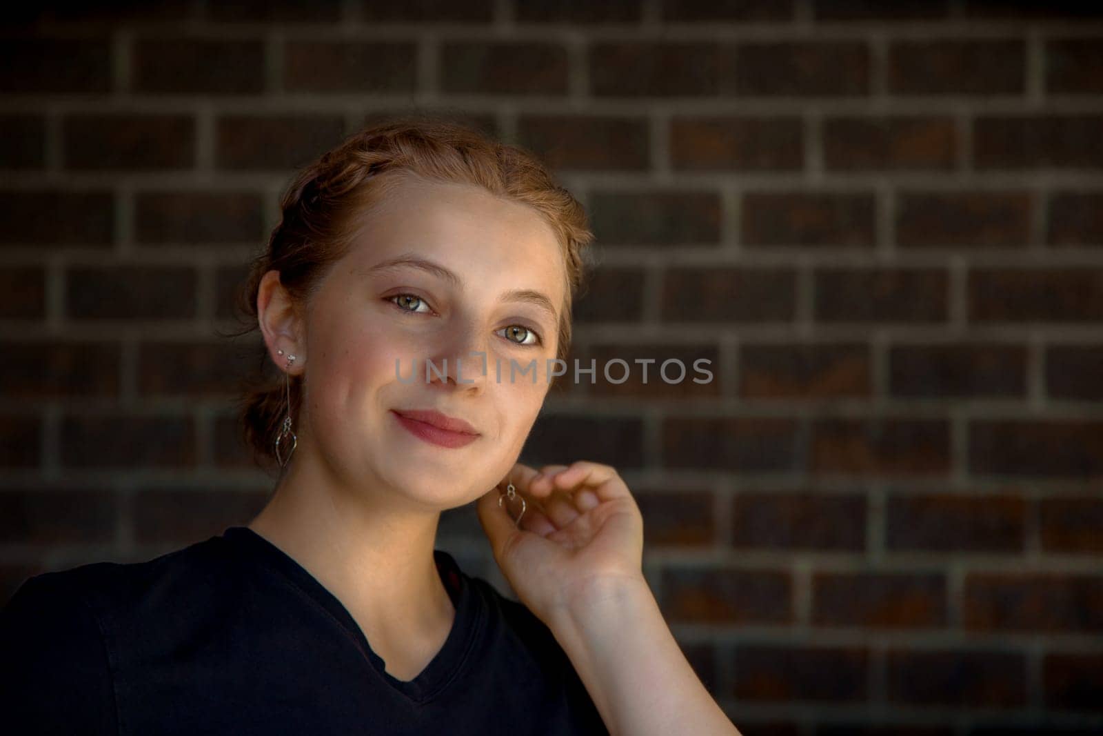 young blonde woman holding her ear jewelry luxury hairstyle elegance black fashion beauty on brick background