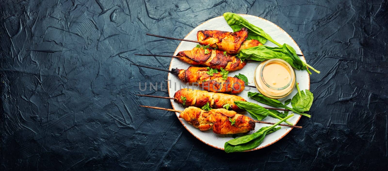 Roasted chicken meat. Chicken breast on a skewer. Meat kebab or shashlik with peanut sauce.