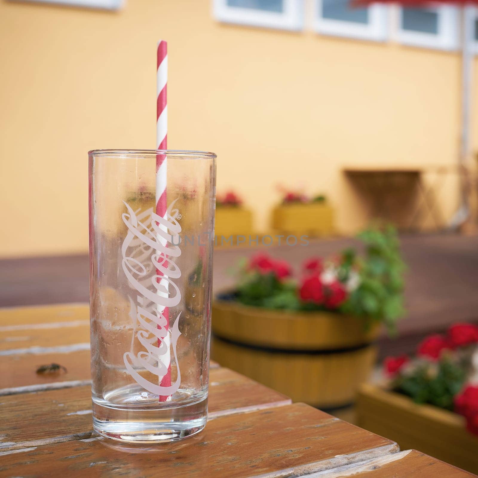 empty Coca-Cola glass with straw on table in restaurant