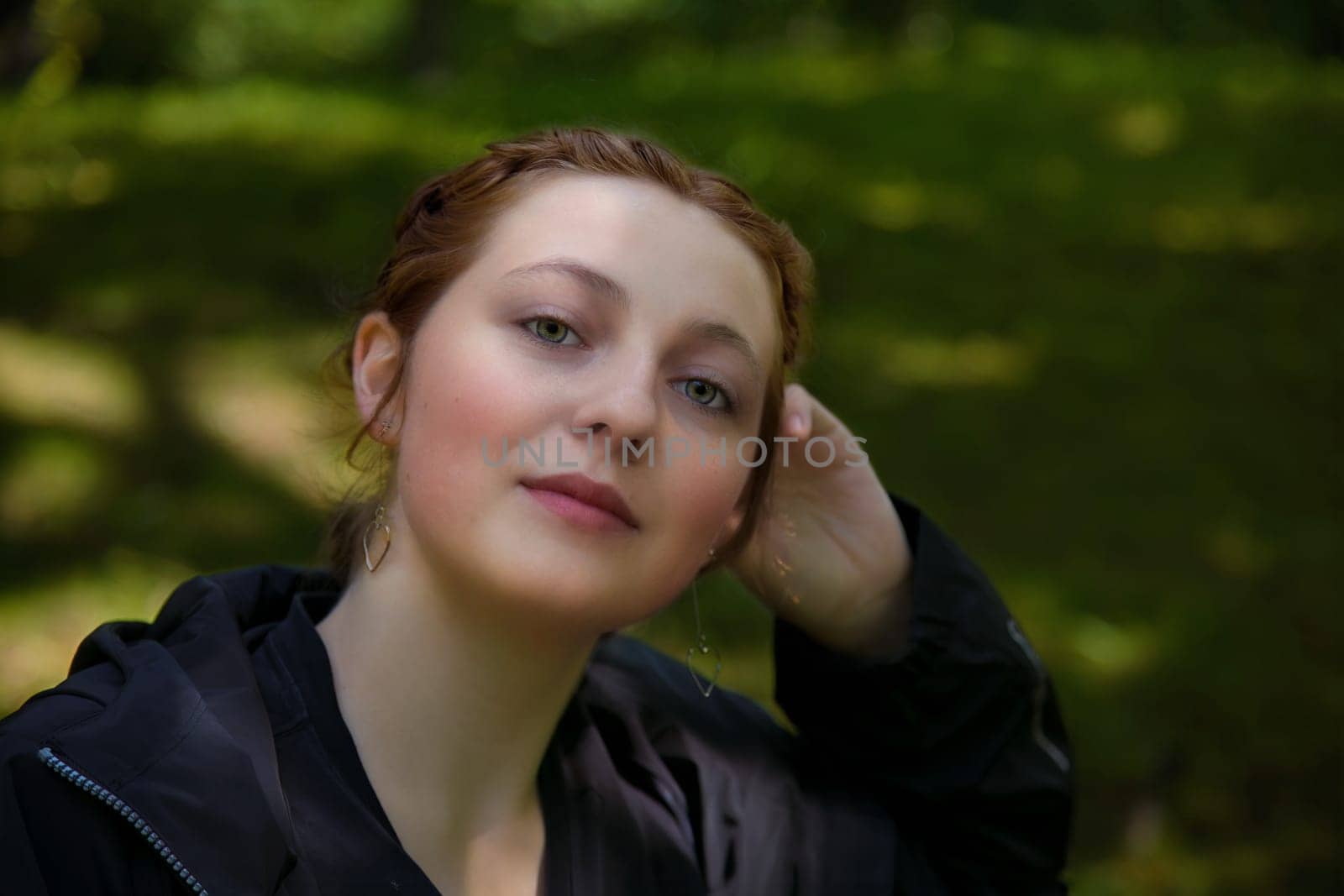 young beautiful redhead woman sitting in a park student portrait outside