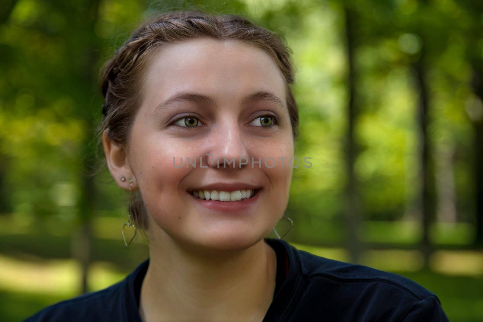 young 18-year-old woman with short hair who smiles outside smiling girl in a park