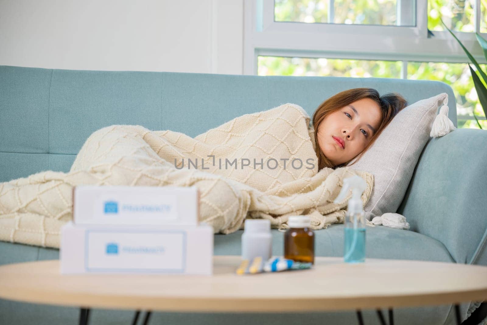 Asian beautiful female use pharmacy first aid kit box delivery service from hospital, Young woman tired sick she sleep and resting on sofa after take medicines pills in living room at home, healthcare