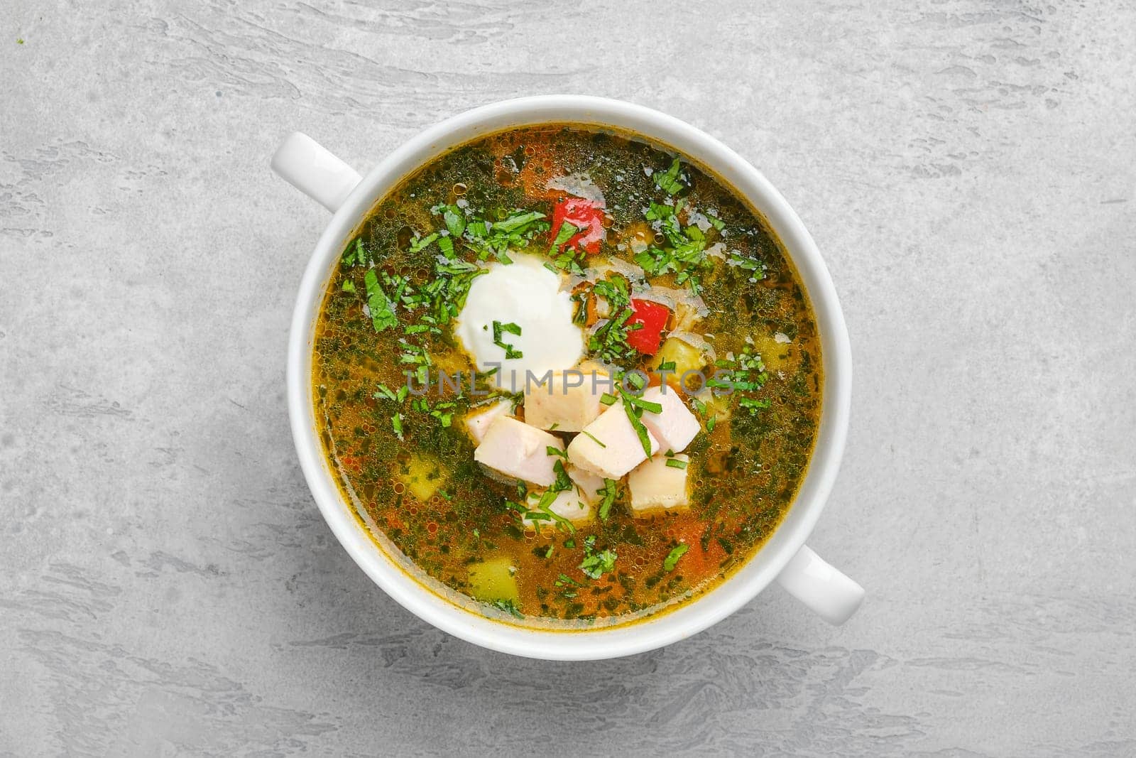 Top view of vegetable soup with chicken fillet and sour cream