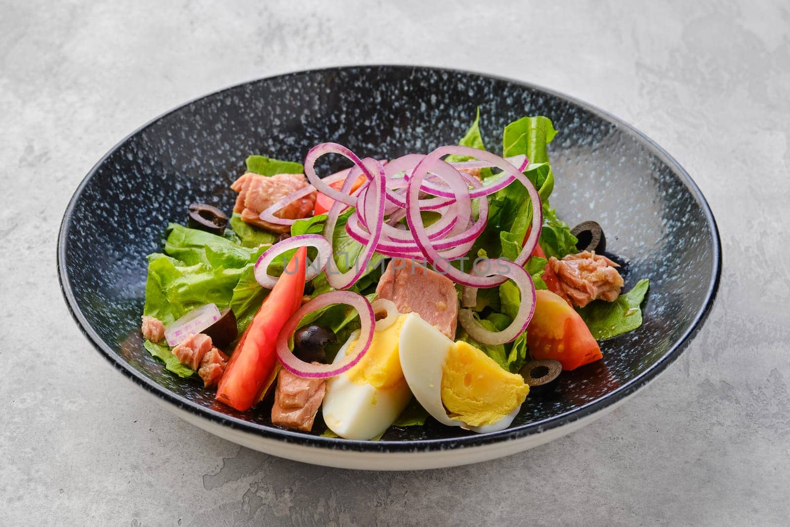 Salad with lettuce, salmon, tomato, boiled egg and onion with olives