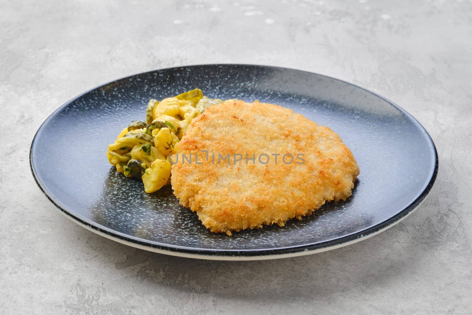 Pork schnitzel with potato and pickled cucumber in mustard sauce
