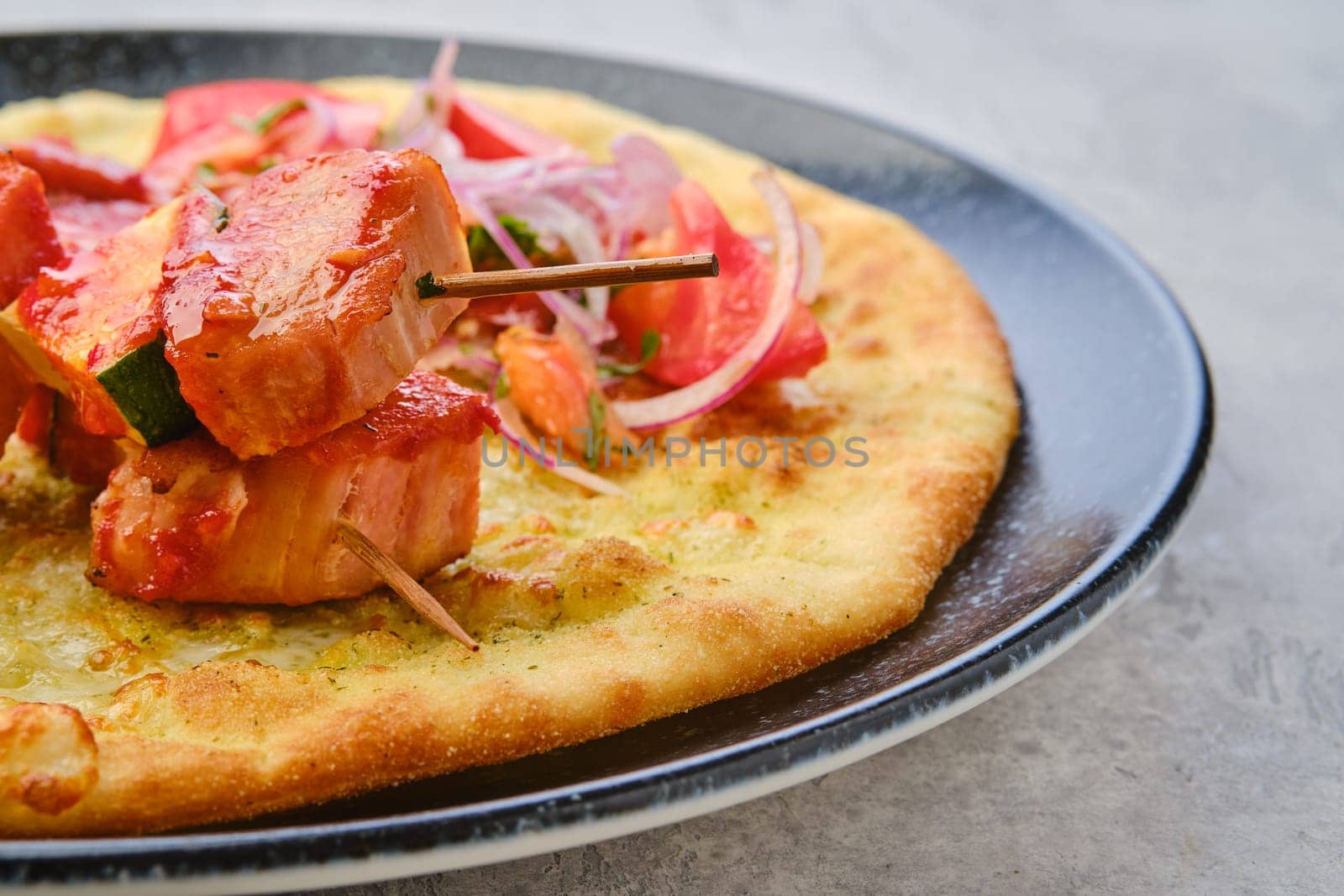 Closeup view of shashlik served on tortilla with tomato and red onion