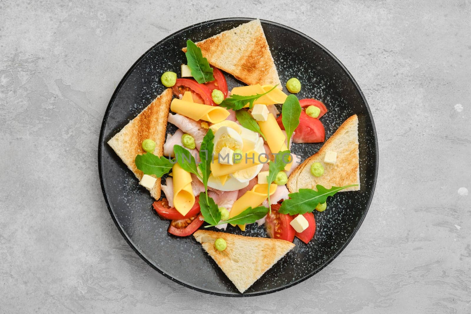 Top view of triangular pieces of toast, ham, boiled egg, cheddar and tomato