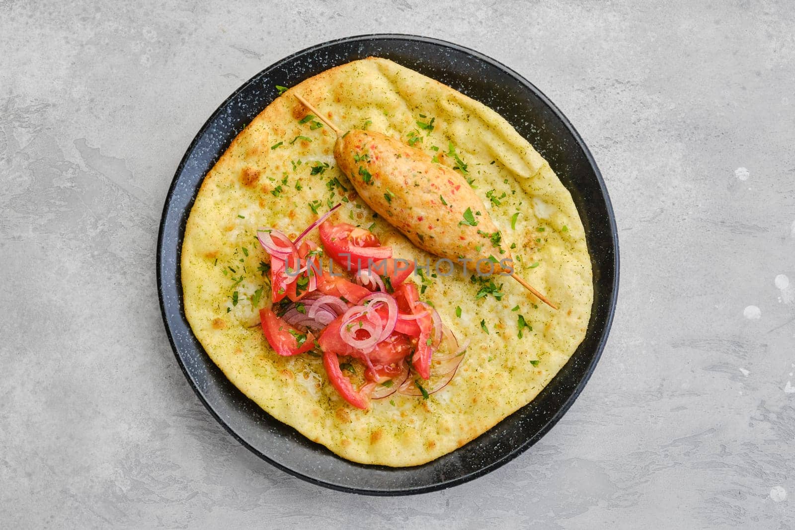 Top view of kebab served on tortilla with tomato and red onion