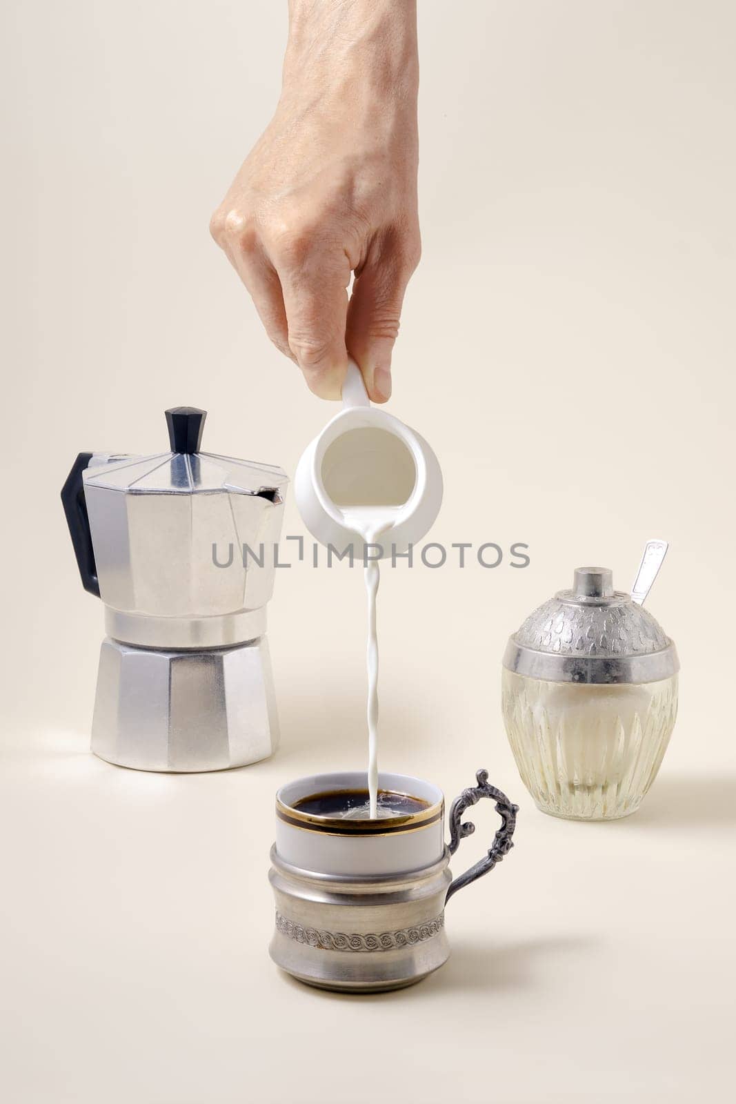 Coffee concept - pouring milk in cup of coffee, geyser coffee maker and shugar