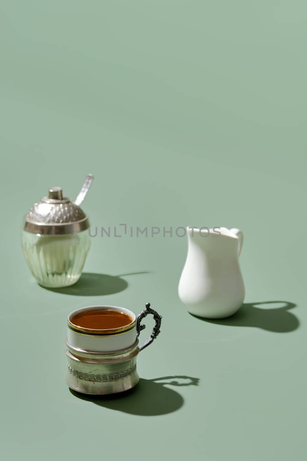 Coffee concept - cup of coffee, milk pot and shugar (focus on foreground)