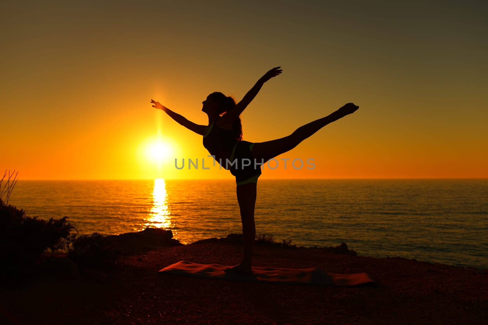 Backlight ballerina silhouette danding ballet at sunset on the beach