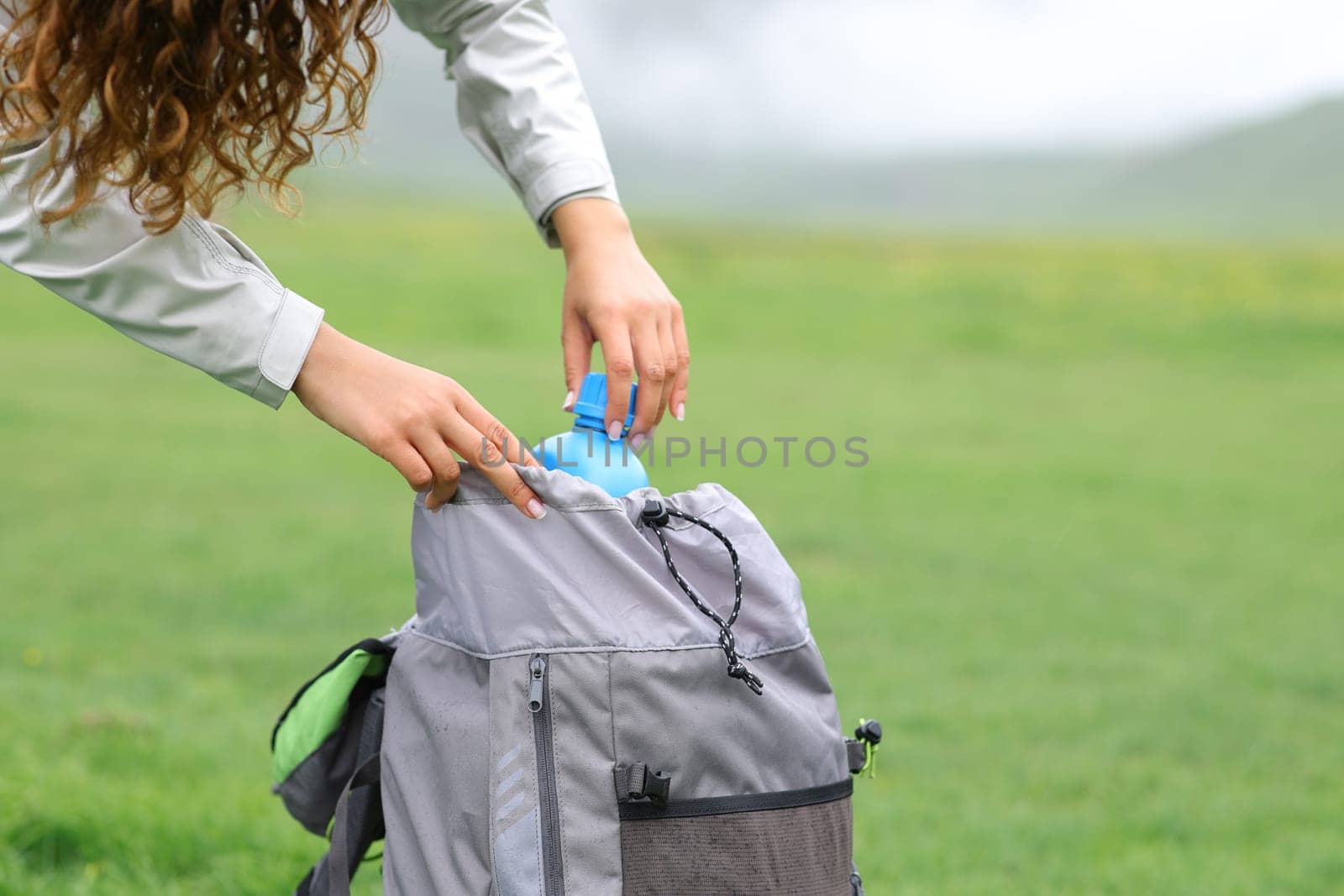 Close up of a hiker hands putting canteen in a backpack