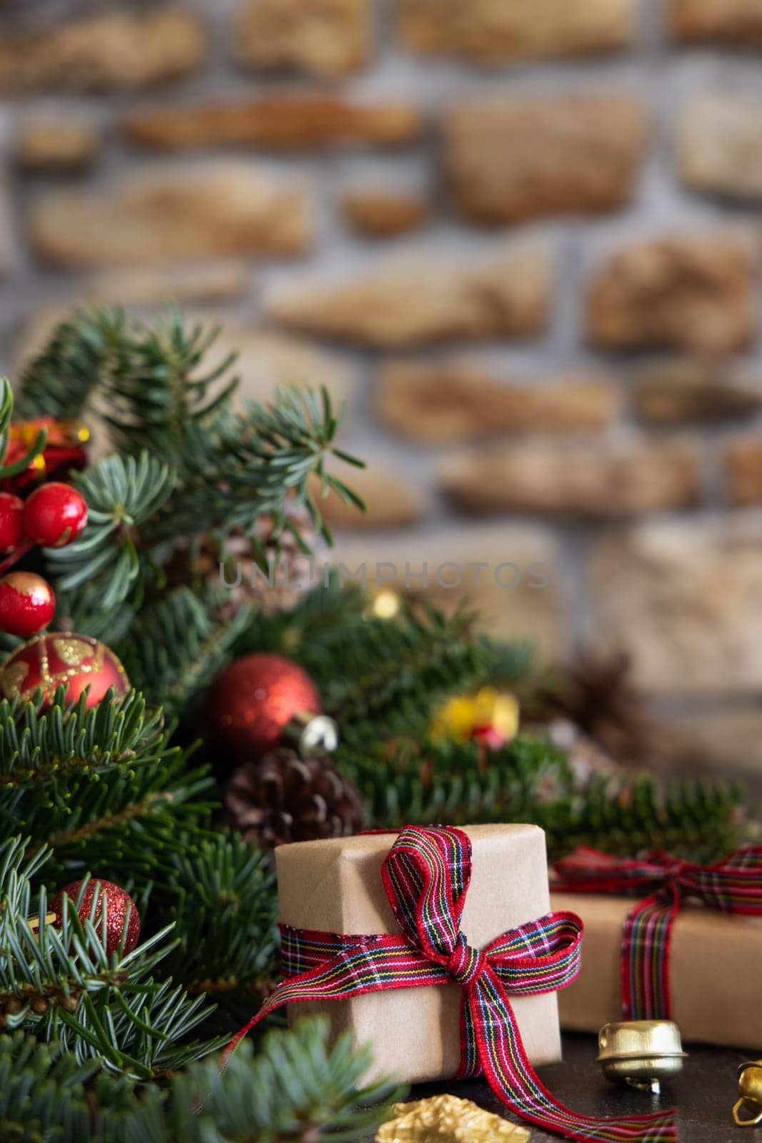 Wrapped gift boxes between Christmas decorations, pine cones and green fir branches close up against stone wall. Christmas or New Year Holiday atmosphere flat lay