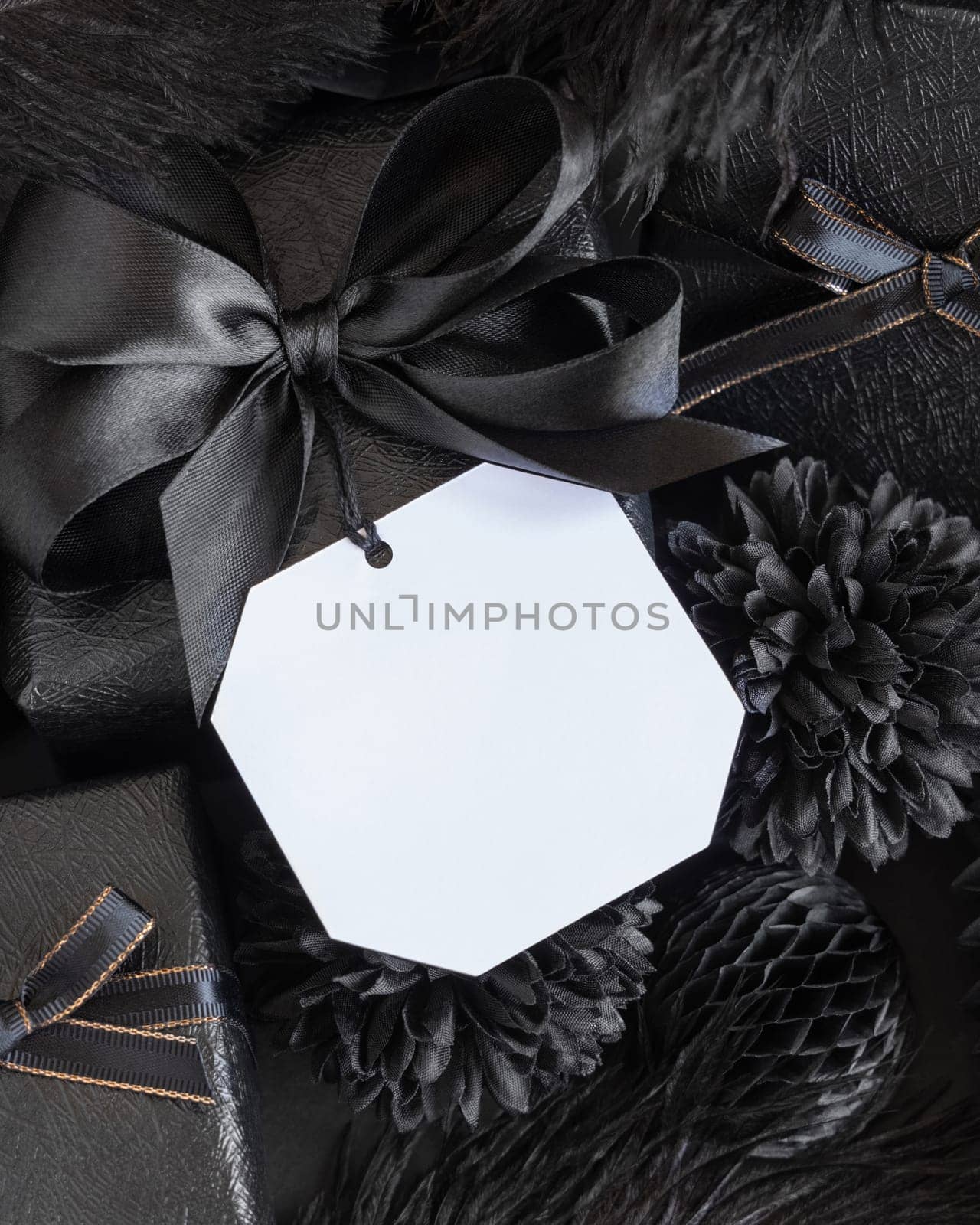Wrapped Gift Boxes with black paper flowers and decorations and square gift tag, mockup, copy space. Dark composition with blank label card for Birthday, Anniversary or black party present