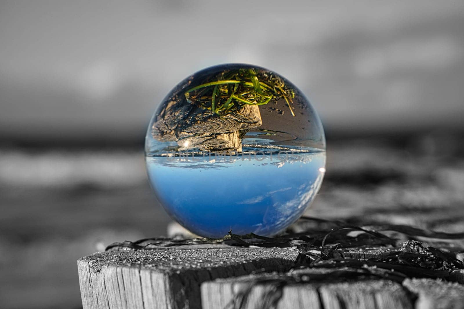 glass globe on the beach of the baltic sea. Black and white photo with a color glass ball