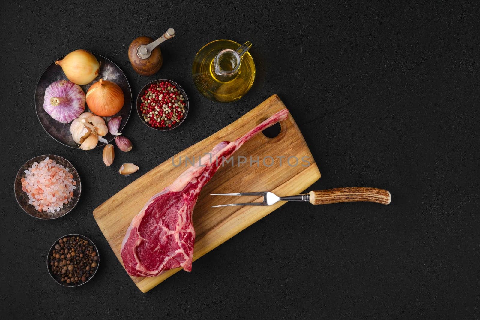 Overhead view of raw beef cowboy steak with spice and seasoning ready for cooking