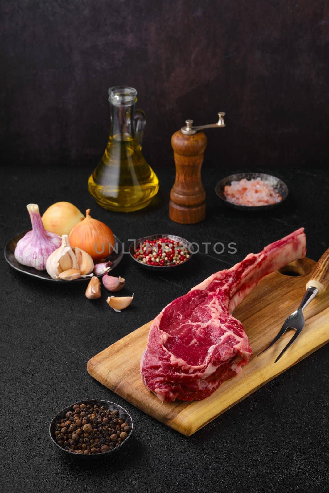 Raw beef cowboy steak with spice and seasoning ready for cooking