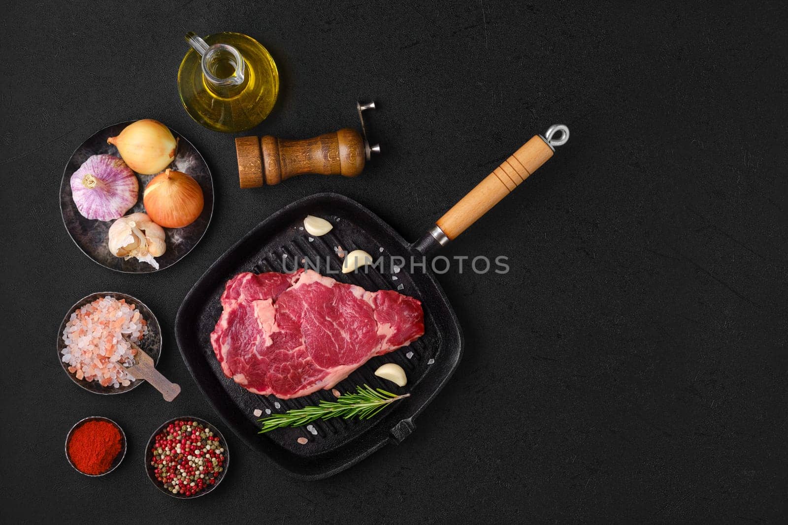 Overhead view of raw ribeye steak, premium beef boneless meat on cast-iron pan
