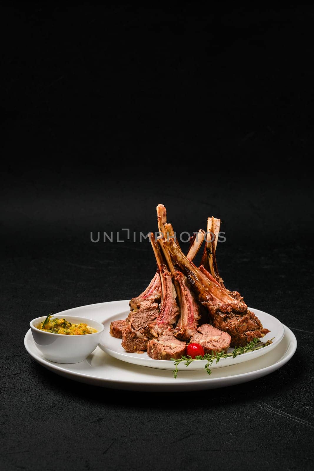 Grilled rack of lamb on a plate with spicy sauce