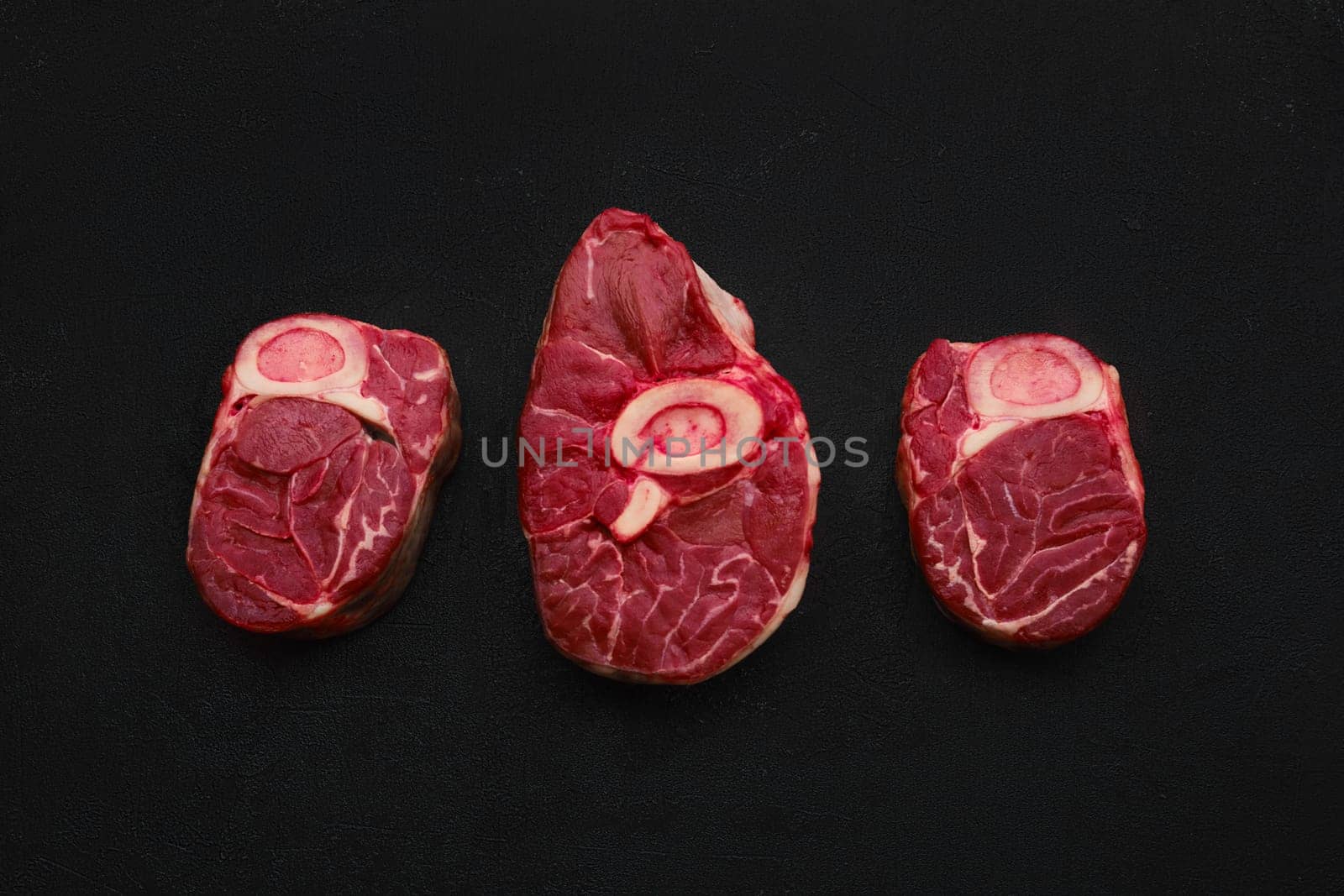 Overhead view of tree raw beef shank cross cut, ossobuco on back background