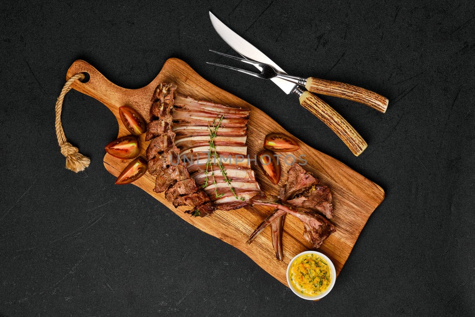 Overhead view of grilled ribs of lamb on a plate with spicy sauce