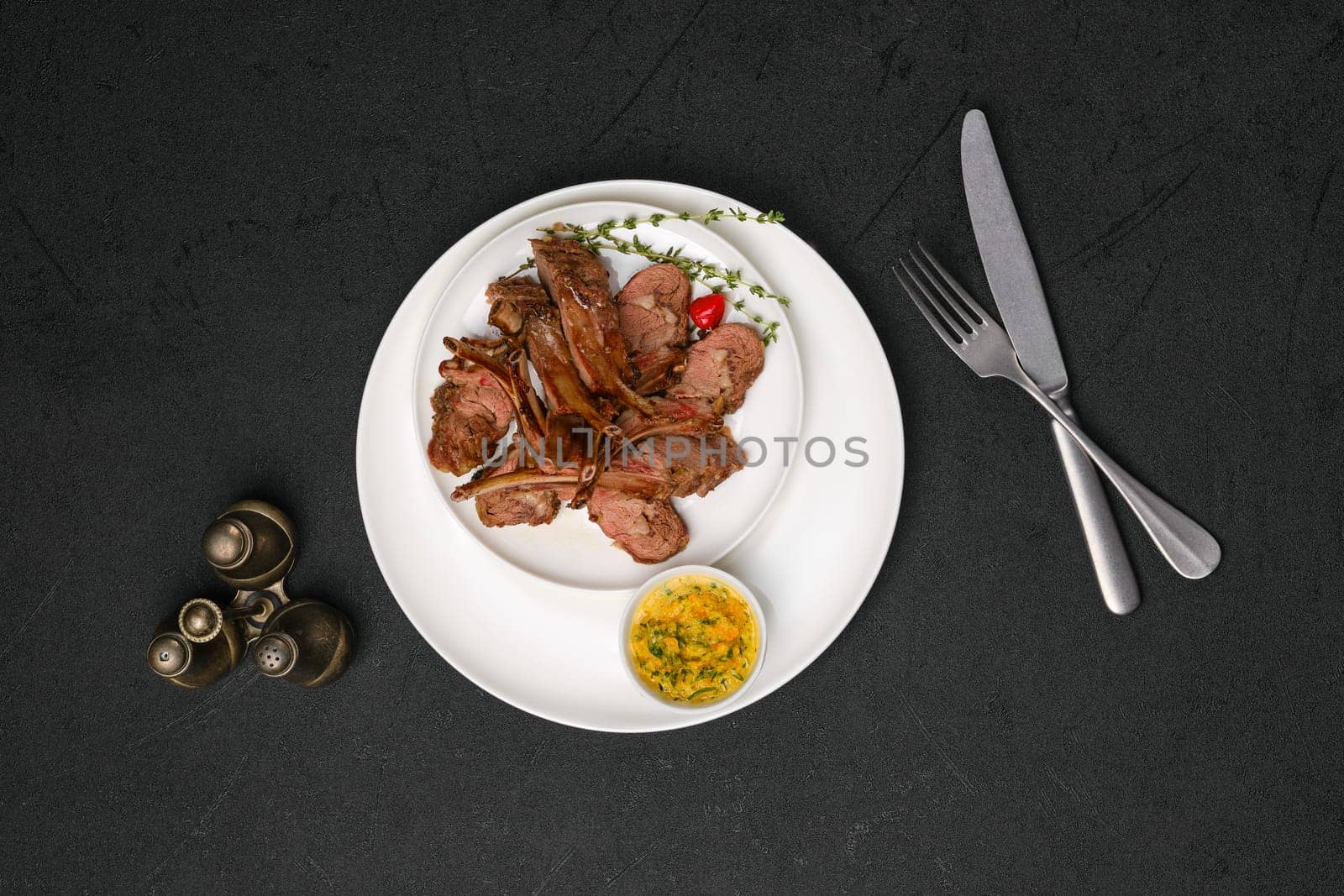 Overhead view of grilled rack of lamb on a plate with spicy sauce