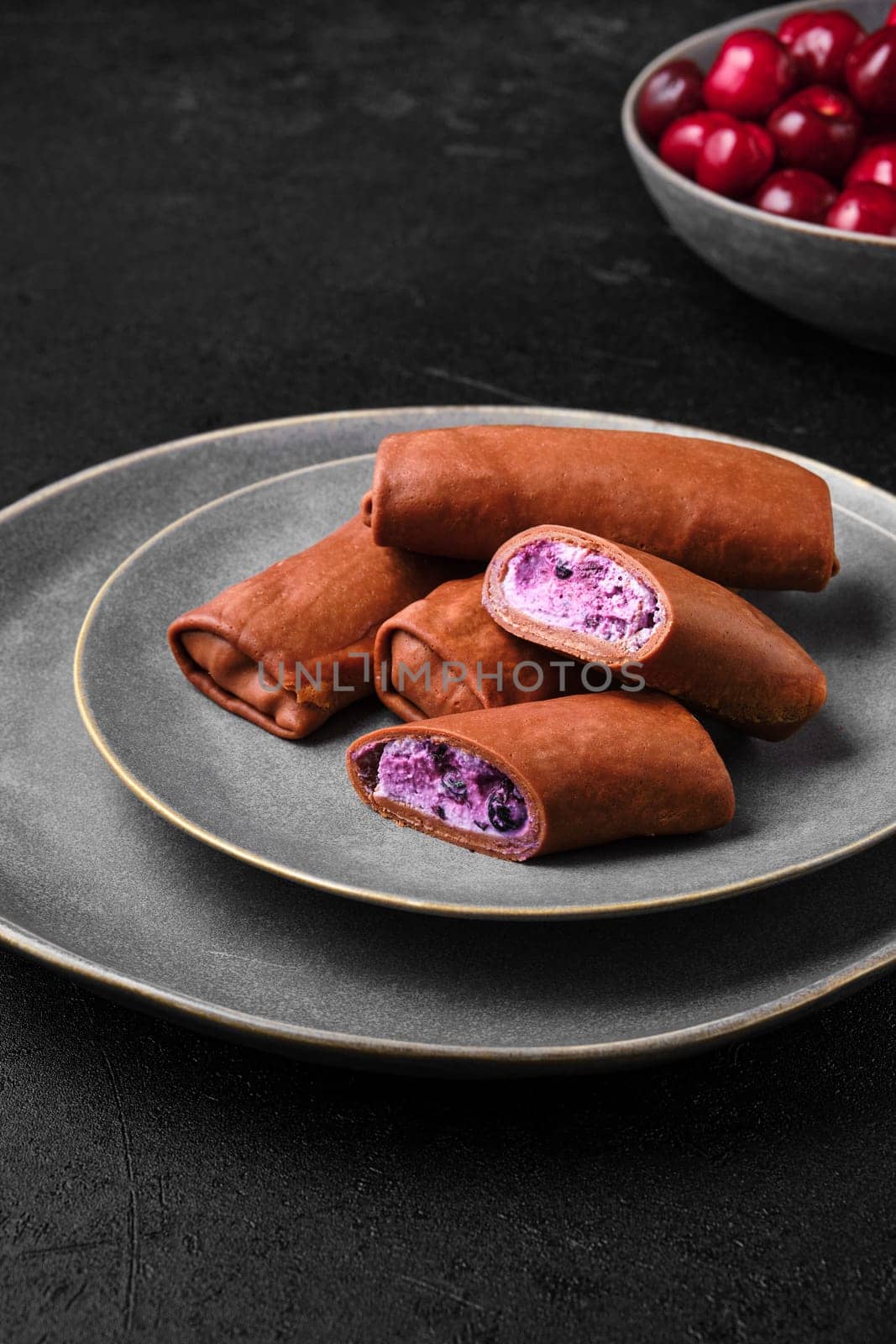 Thin chocolate pancakes stuffed with curd, blueberry and cherry
