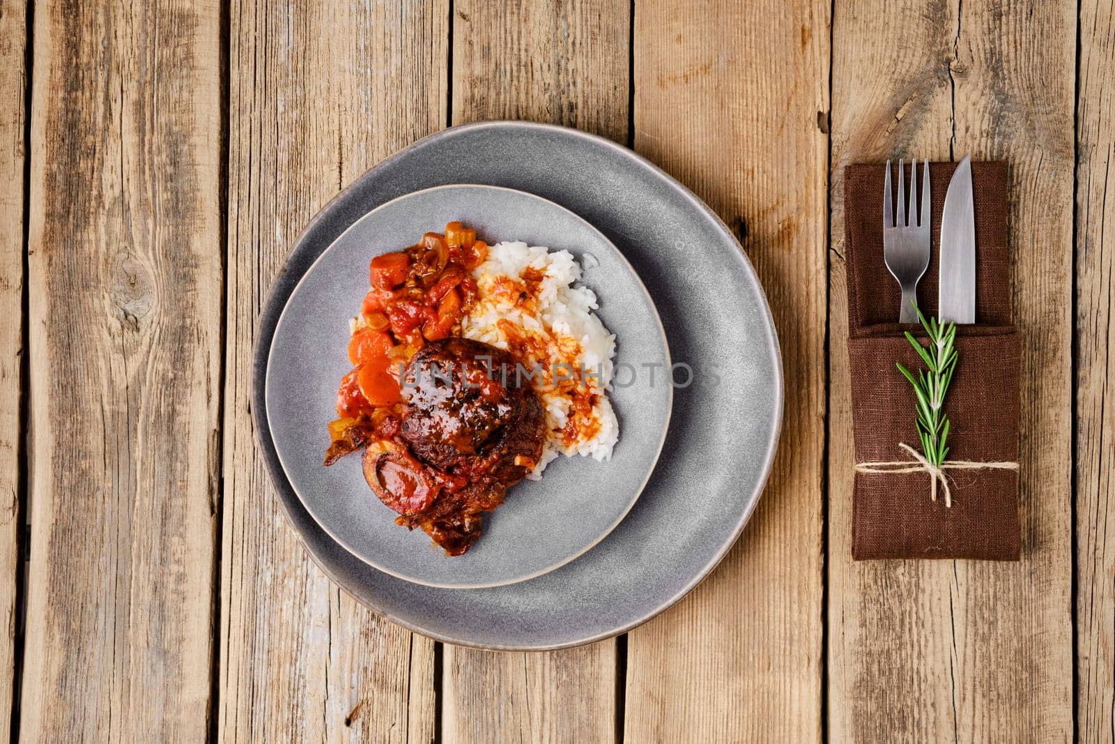 Overhead view of plate with ossobuco on wooden table