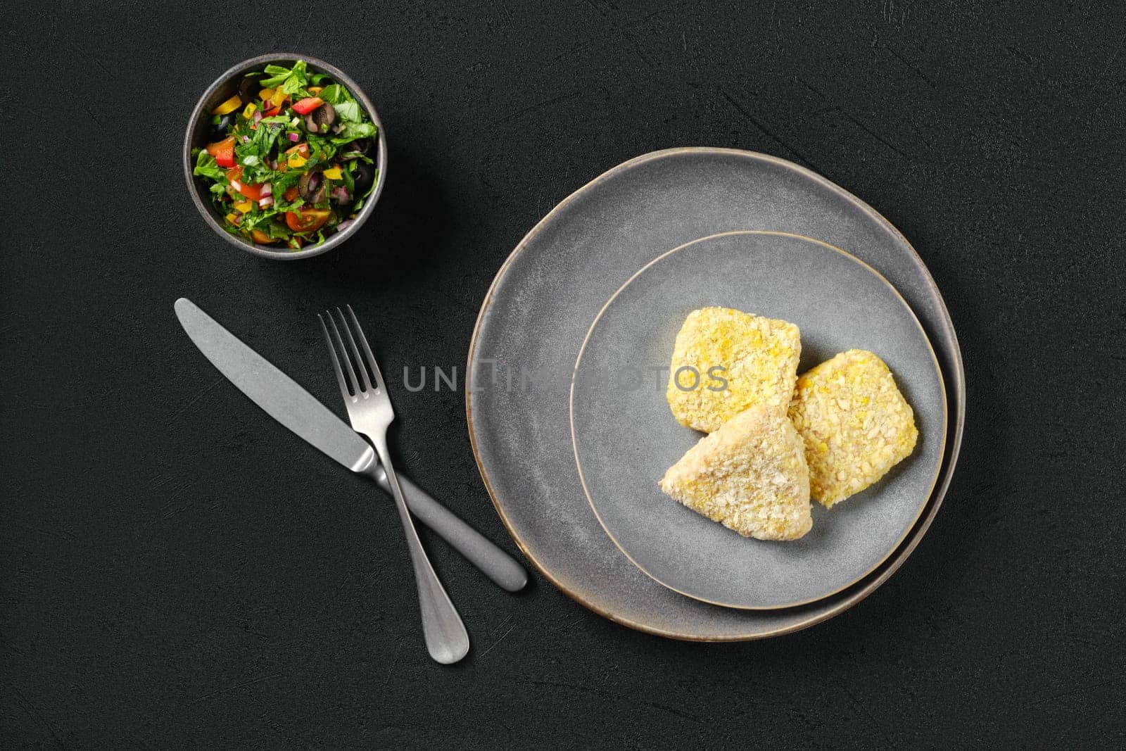 Top view of semifinished squid cutlet in breading on a plate