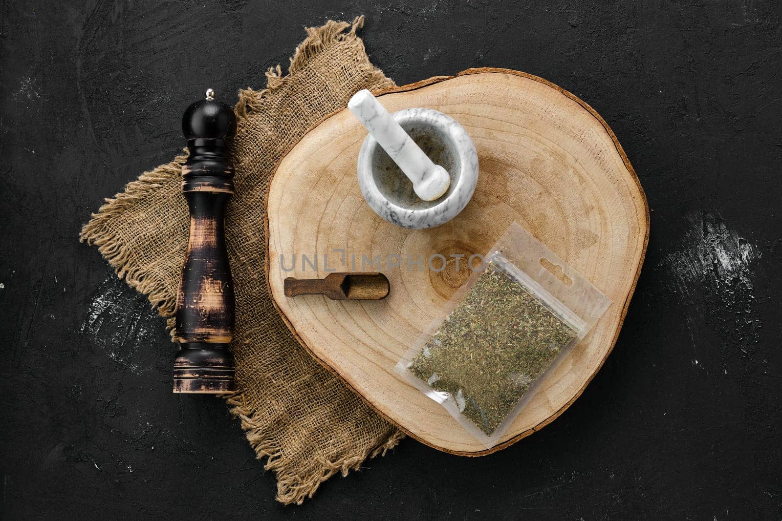 Wooden cross section with Provencal herbs in plastic package and stone mortar and mill