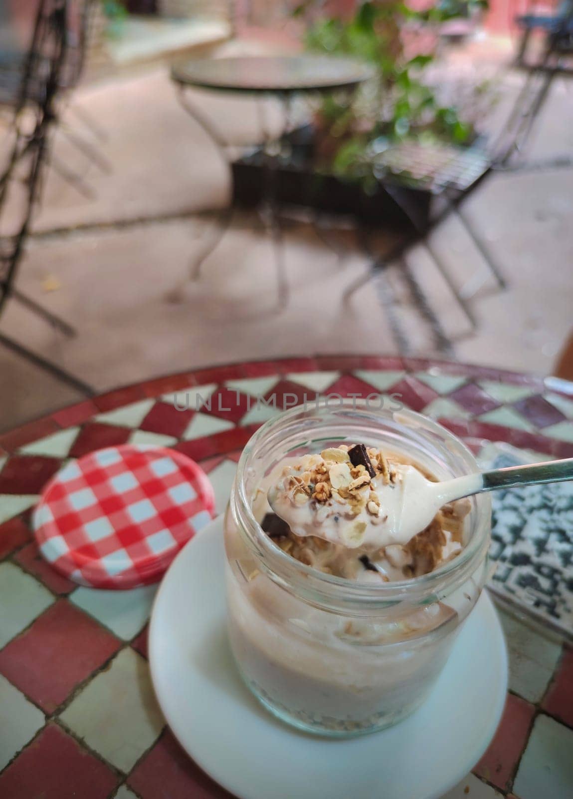 Spoonful of yogurt with muesli from glass jar. QR code sticker over glazed tile mosaic table