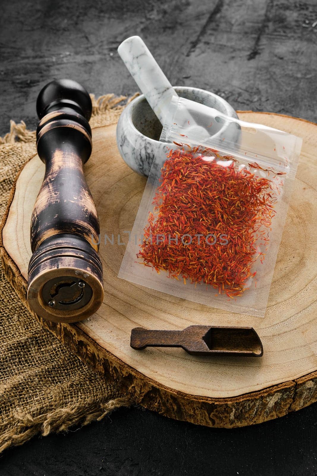 Wooden cross section with saffron in plastic package and stone mortar and mill