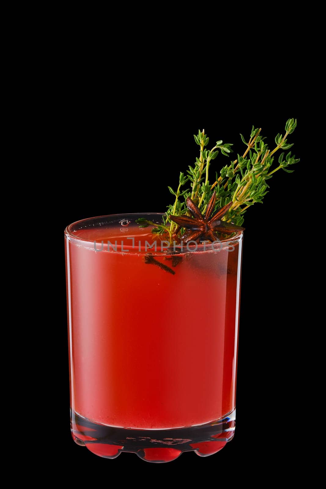 Hot cranberry winter drink with thyme, cloves and anise isolated on black