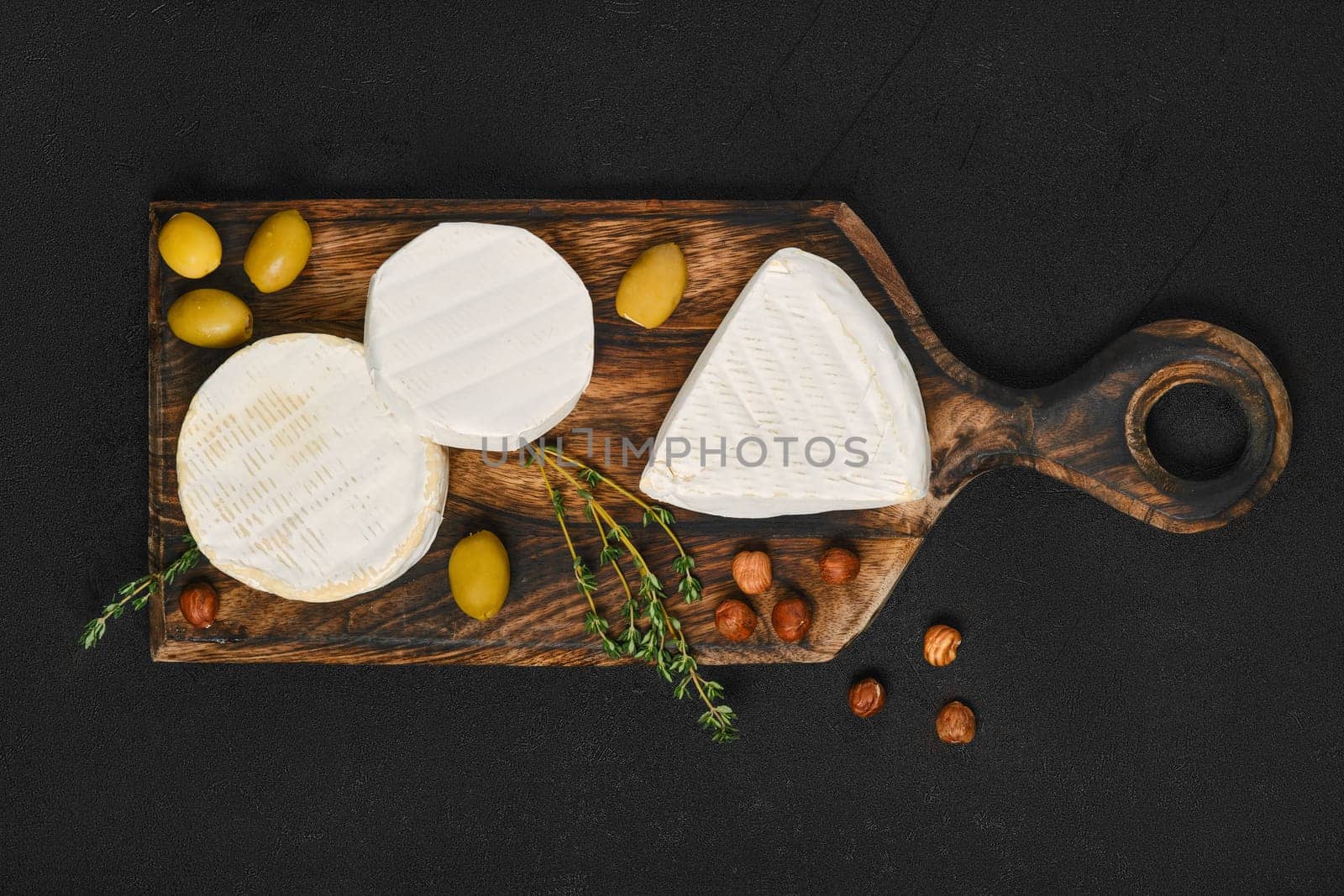 Top view of cheese platter. Assortment of brie and camembert cheese on wooden cutting board.