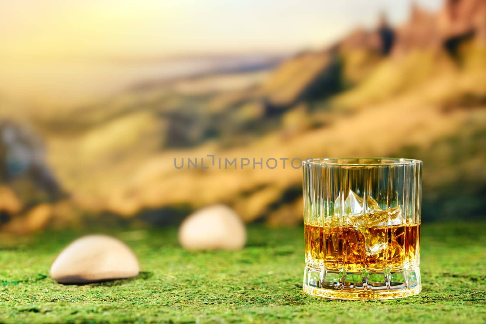 Facetted glass of peat whiskey on green moss