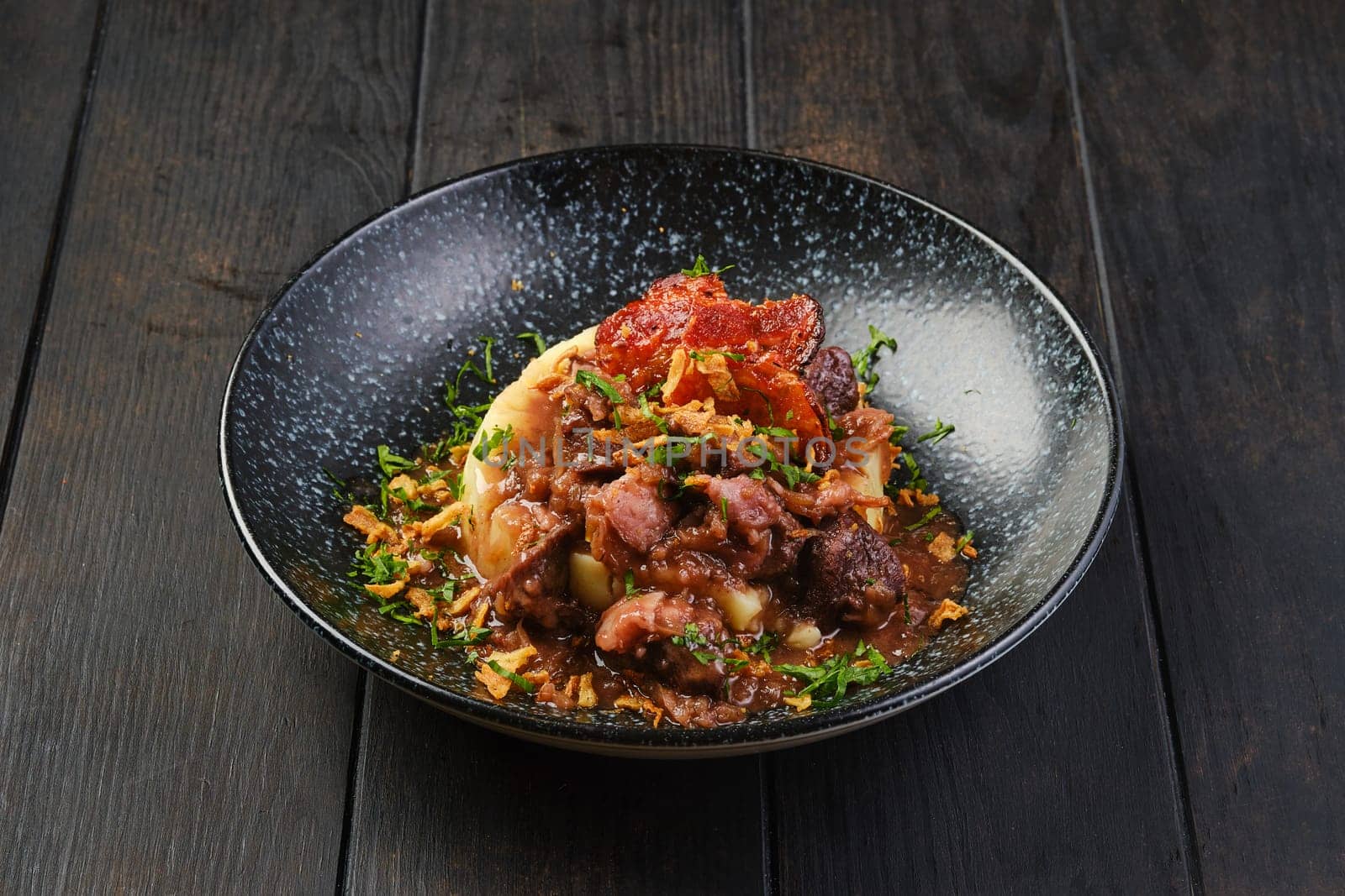 Beef goulash with bacon and mashed potato on a table