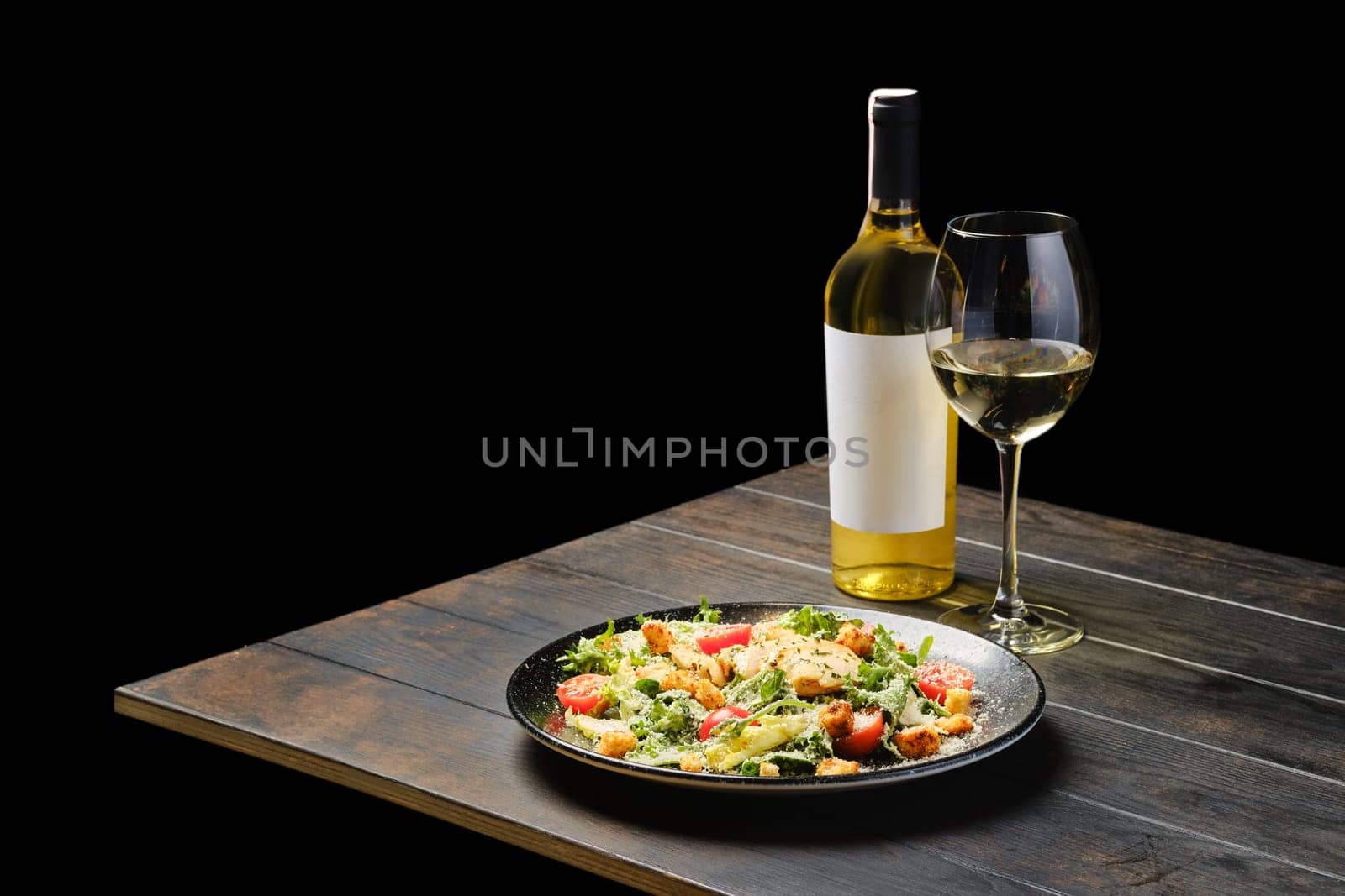 Salad with chicken and fresh vegetables with a wine on a table
