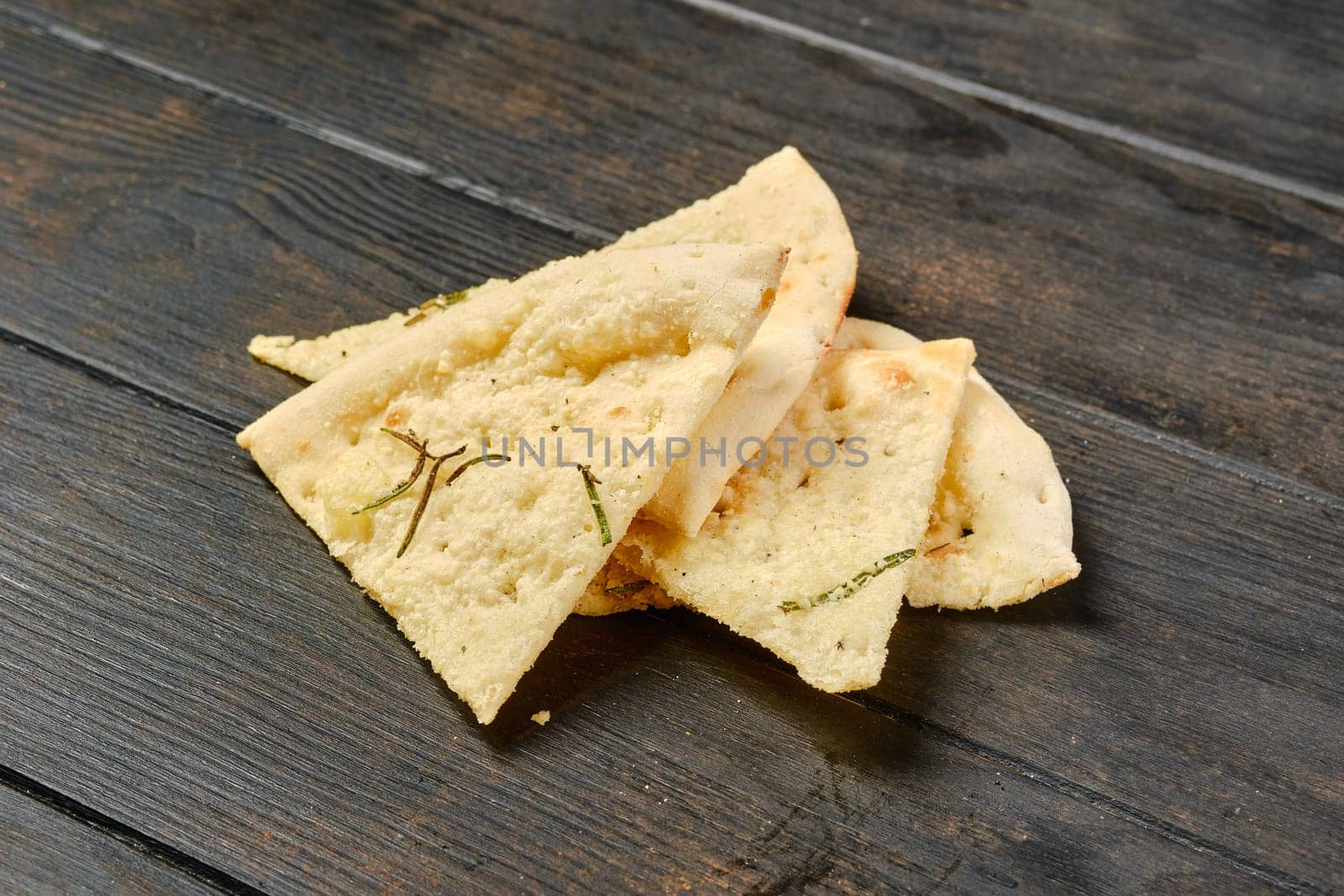 Four pieces of focaccia with herbs on wooden table