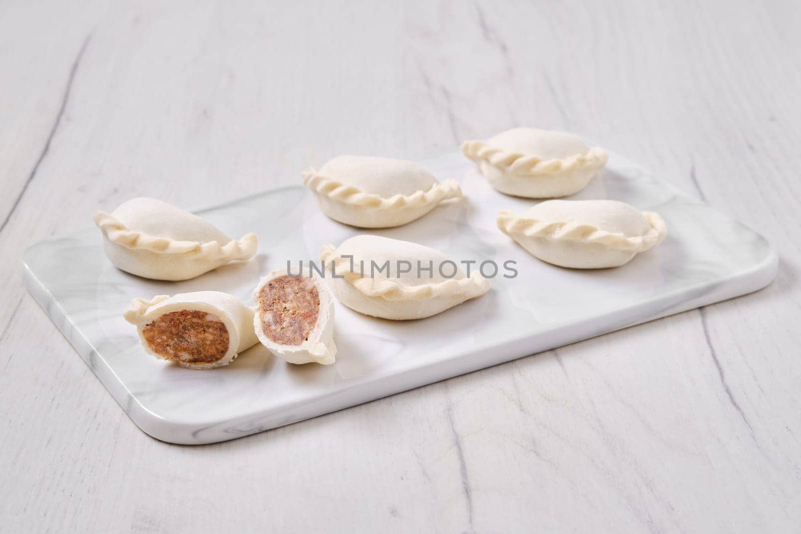 Frozen dumplings stuffed with beef meat and provencal herbs on marble serving plate
