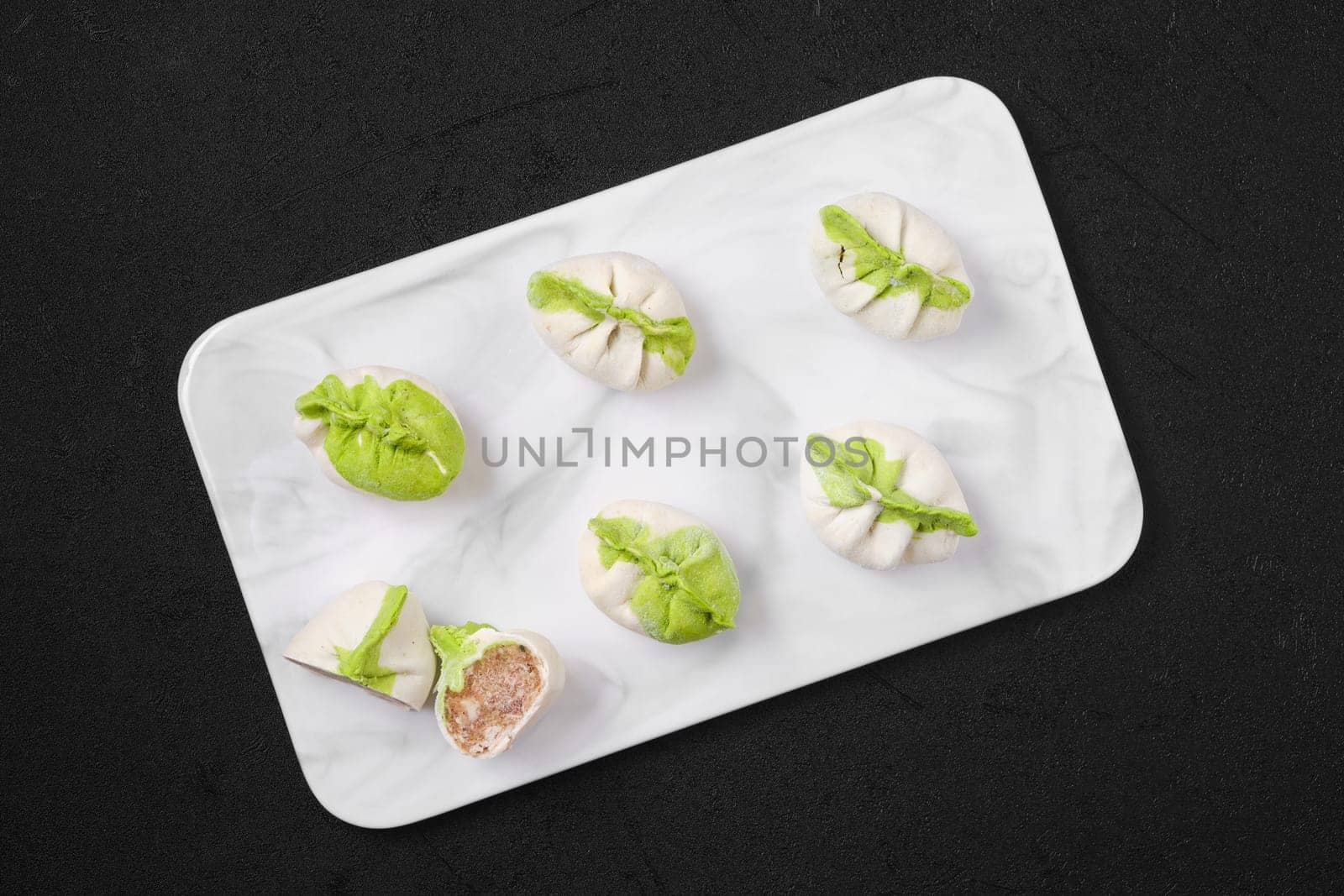 Top view of frozen dumplings stuffed with pork meat and provencal herbs on marble serving plate