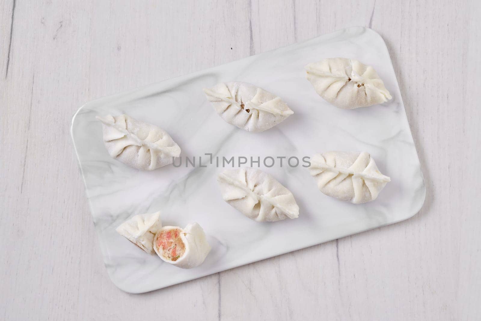 Top view of frozen dumplings stuffed with liver and provencal herbs on marble serving plate