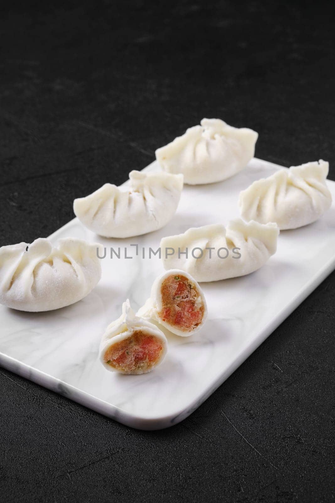 Frozen dumplings stuffed with liver and provencal herbs on marble serving plate