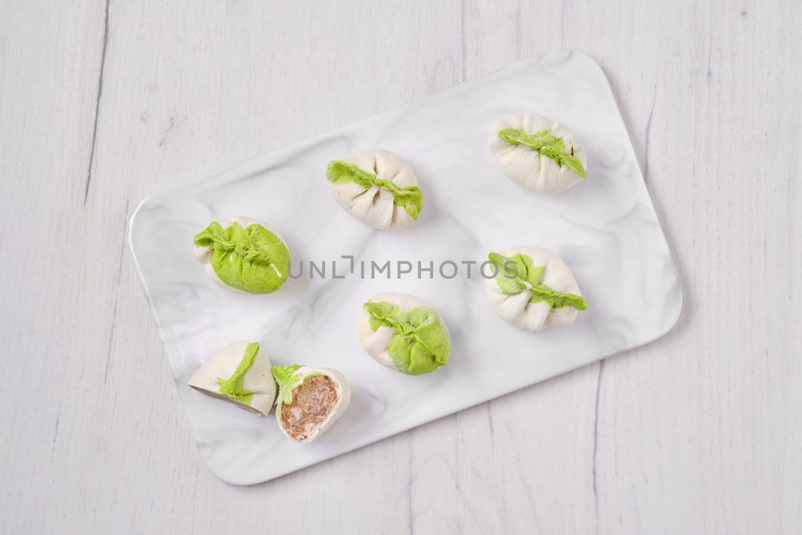 Top view of frozen dumplings stuffed with pork meat and provencal herbs on marble serving plate
