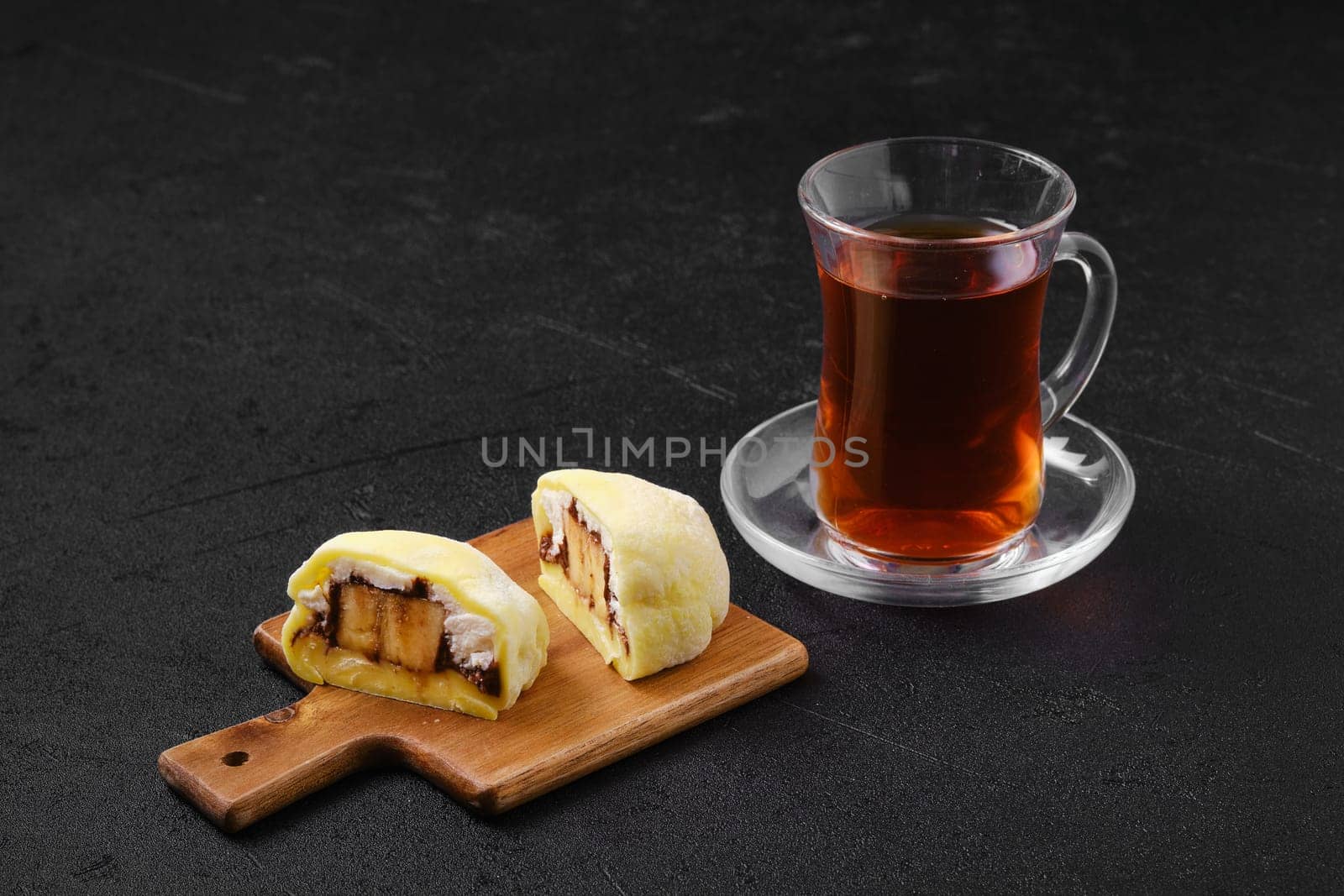 Sweet dessert mochi with banana and chocolate cut on half with fruit tea
