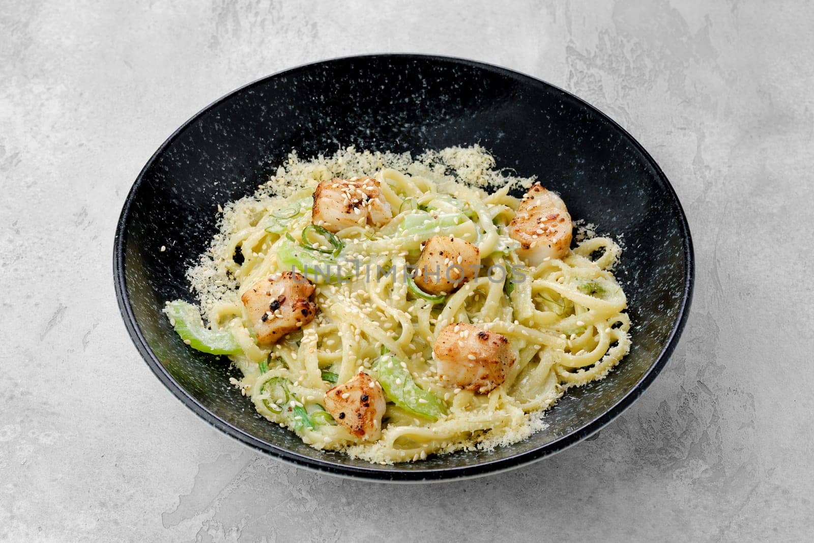 Spaghetti with chuka salad, fried zander fillet and bechamel sauce on a plate