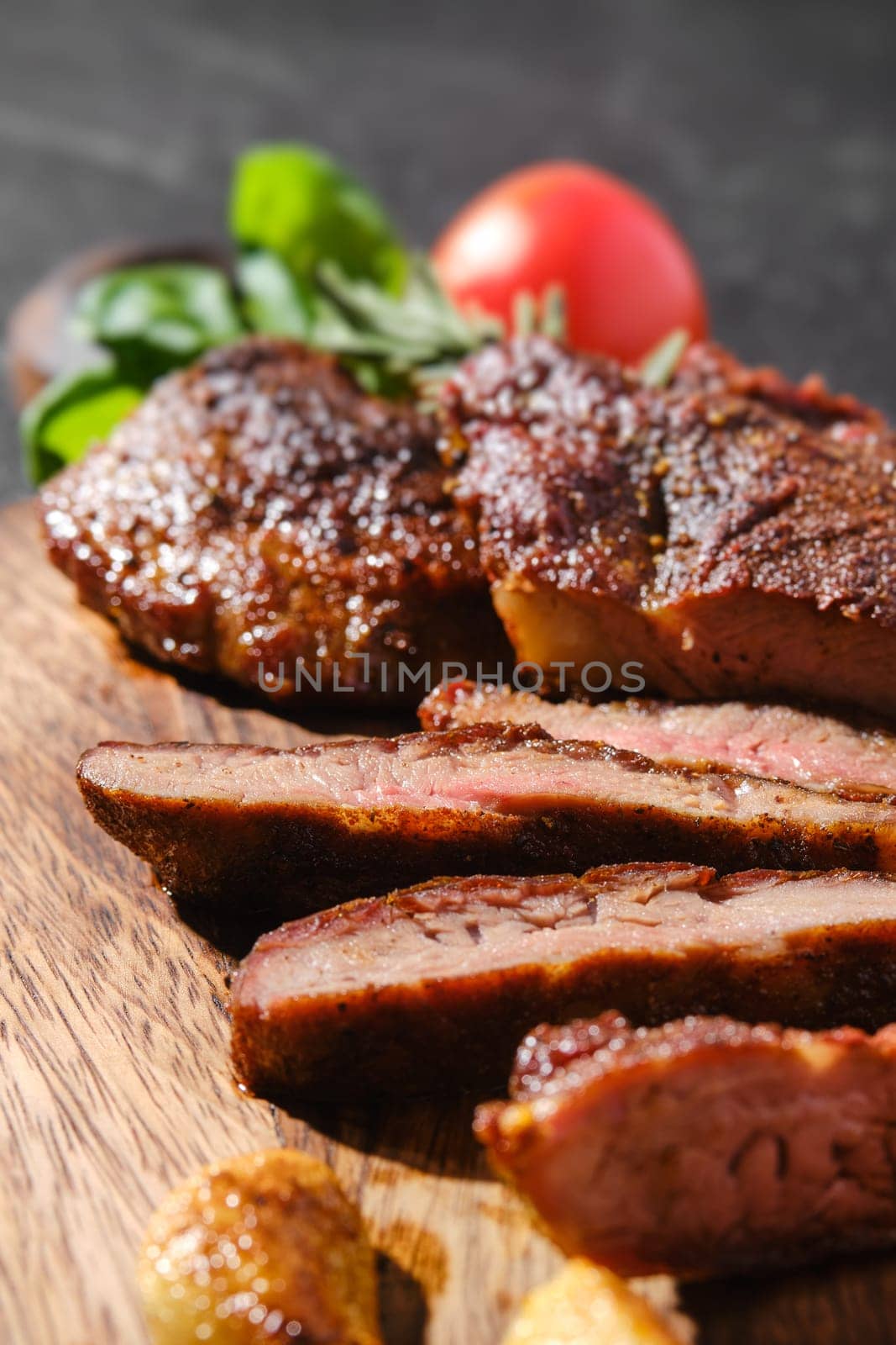 Closeup view of beefsteak spider fried in cast-iron pan, served on wooden cutting board with tomato and basil