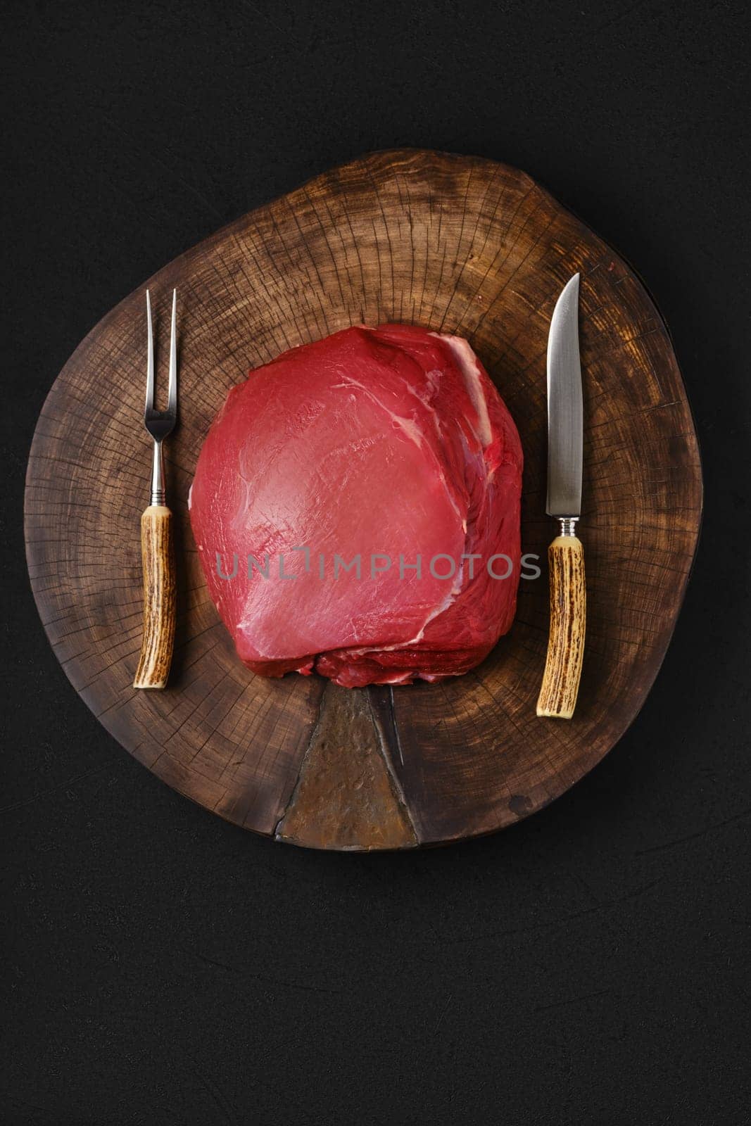 Raw beef top round meat, whole uncut section on wooden slab